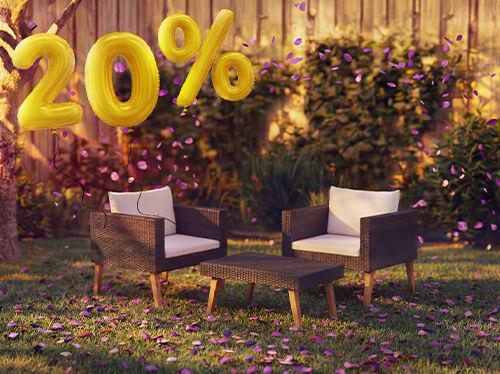Cadeir&otilde;es lounge de rattan para exterior com almofadas e uma pequena mesa num ambiente de jardim, decorados com confetes cor-de-rosa e bal&otilde;es dourados com &laquo;20% de desconto&raquo;, destacando promo&ccedil;&otilde;es sazonais em mobili&aacute;rio lounge de jardim.