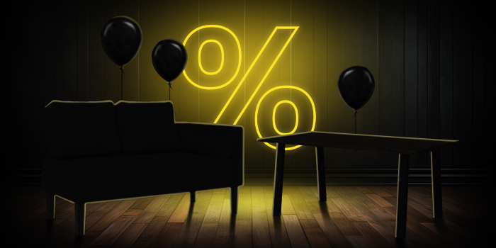 Sofá preto e mesa de madeira com balões pretos em frente a um sinal de percentagem amarelo brilhante num piso de madeira escura.