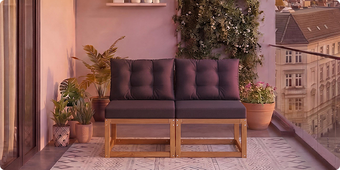  Sofá modular de madeira de dois lugares com almofadas cinzento escuro numa varanda rodeada de vasos de plantas e vista sobre a cidade ao fundo